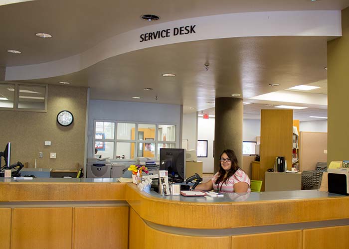 Smiling staff member sitting at the Zuhl Library Service Desk
